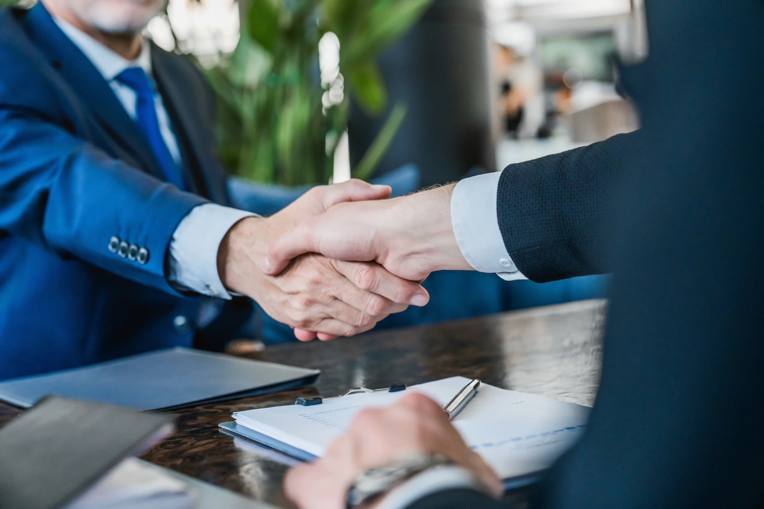 Man shakes hands with malpractice lawyer over signed contract.