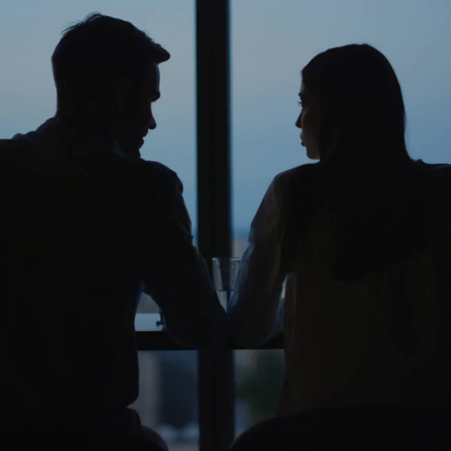 Two people talking in a dark room in silhouette. Secret meeting that may constitute a conflict of interest.