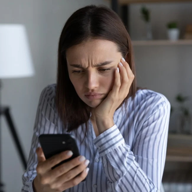 Professional woman looking at her phone angrily